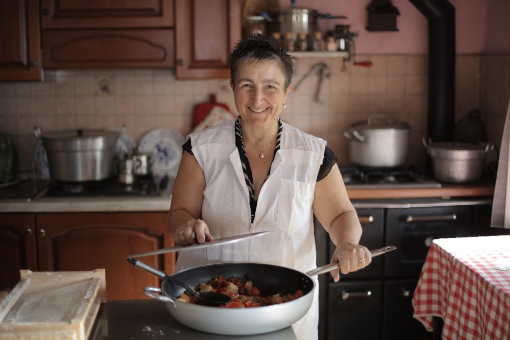 donna anziana che sorride mentre cucina