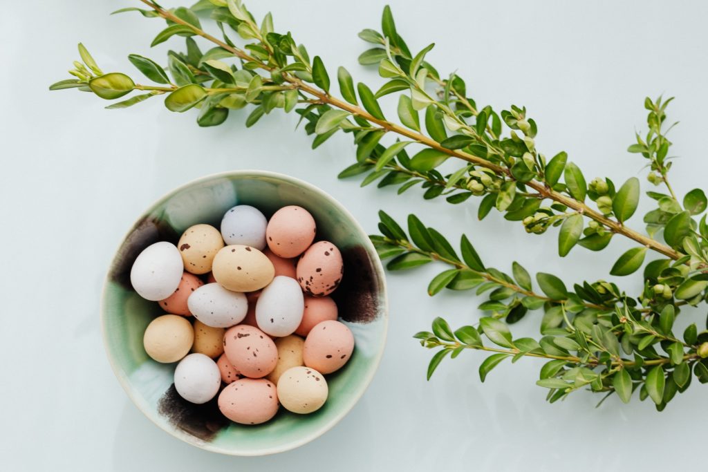 uova di pasqua dentro ad una ciotola con un ramoscello di ulivo